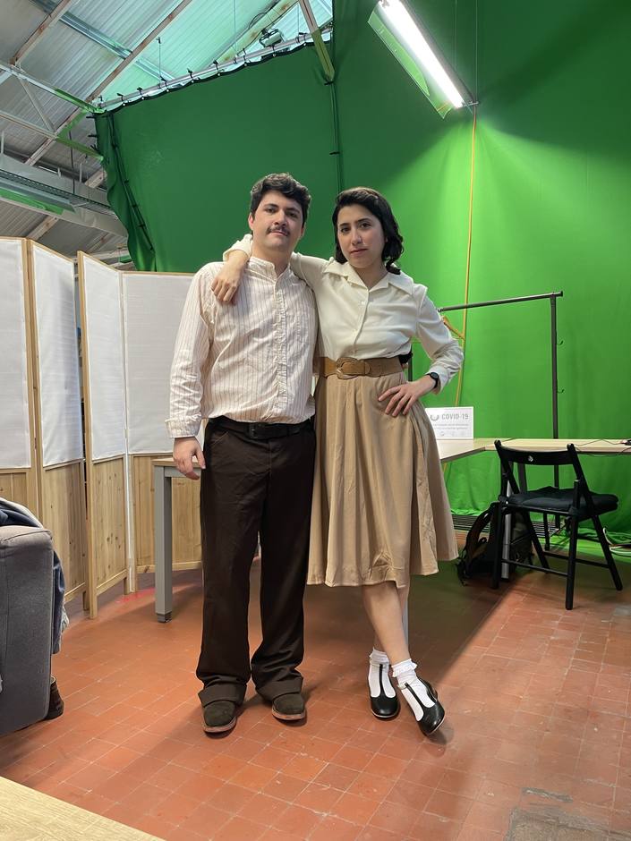 Two actors in period costume in front of a green screen