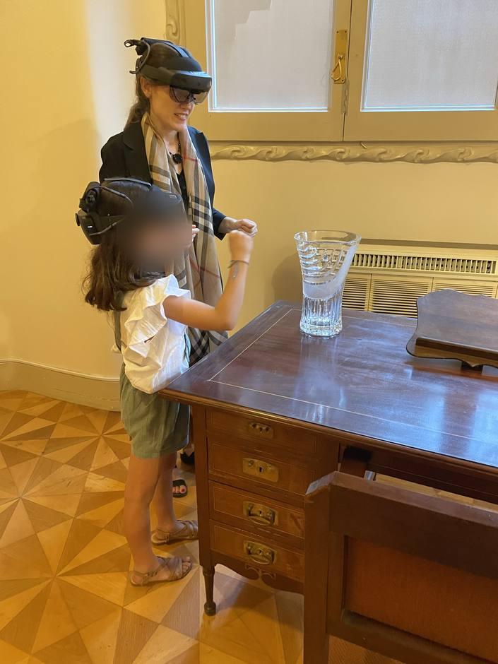 A woman and a child wearing HoloLens 2 interacting with holograms beside an original desk