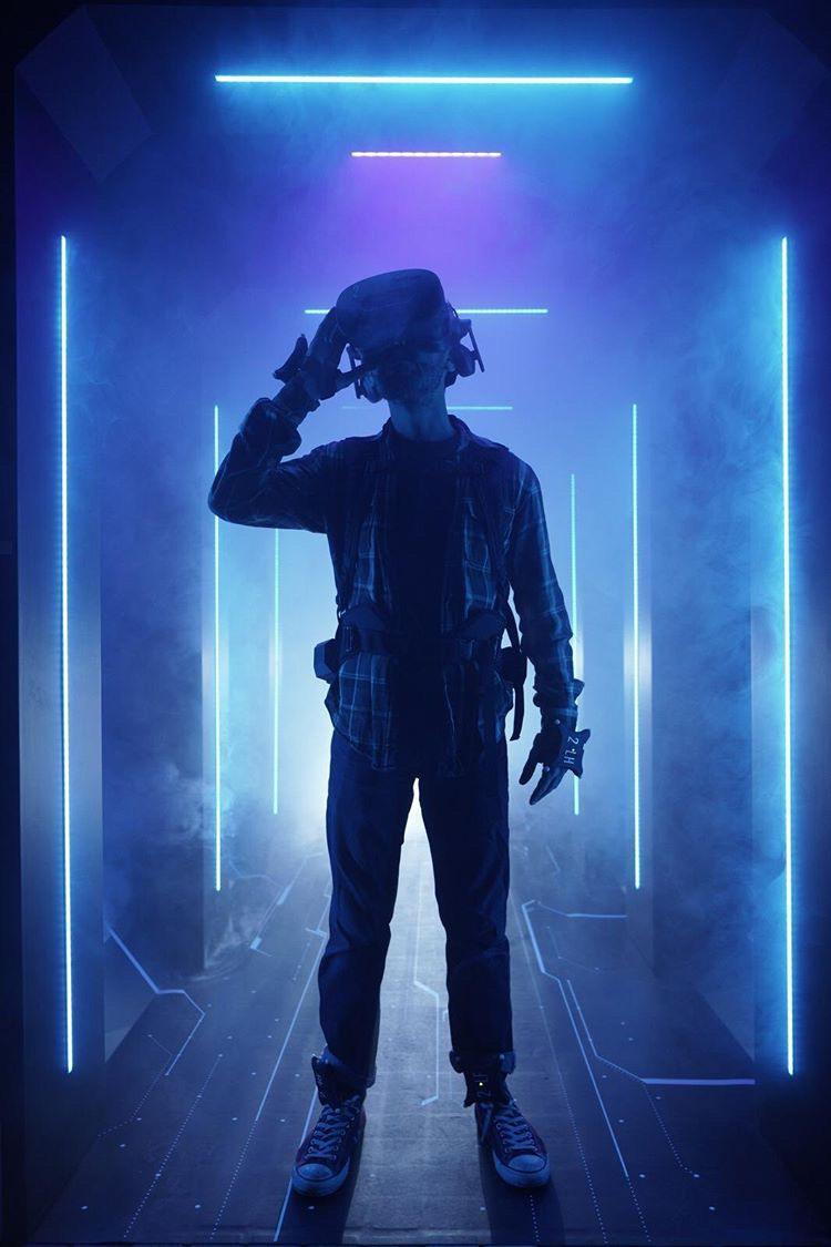 Player in VR headset and tracking suit in a neon corridor